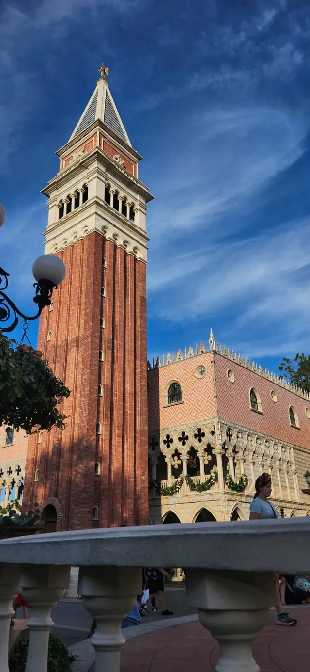 Torre de campanario de ladrillo junto a un edificio de estilo veneciano