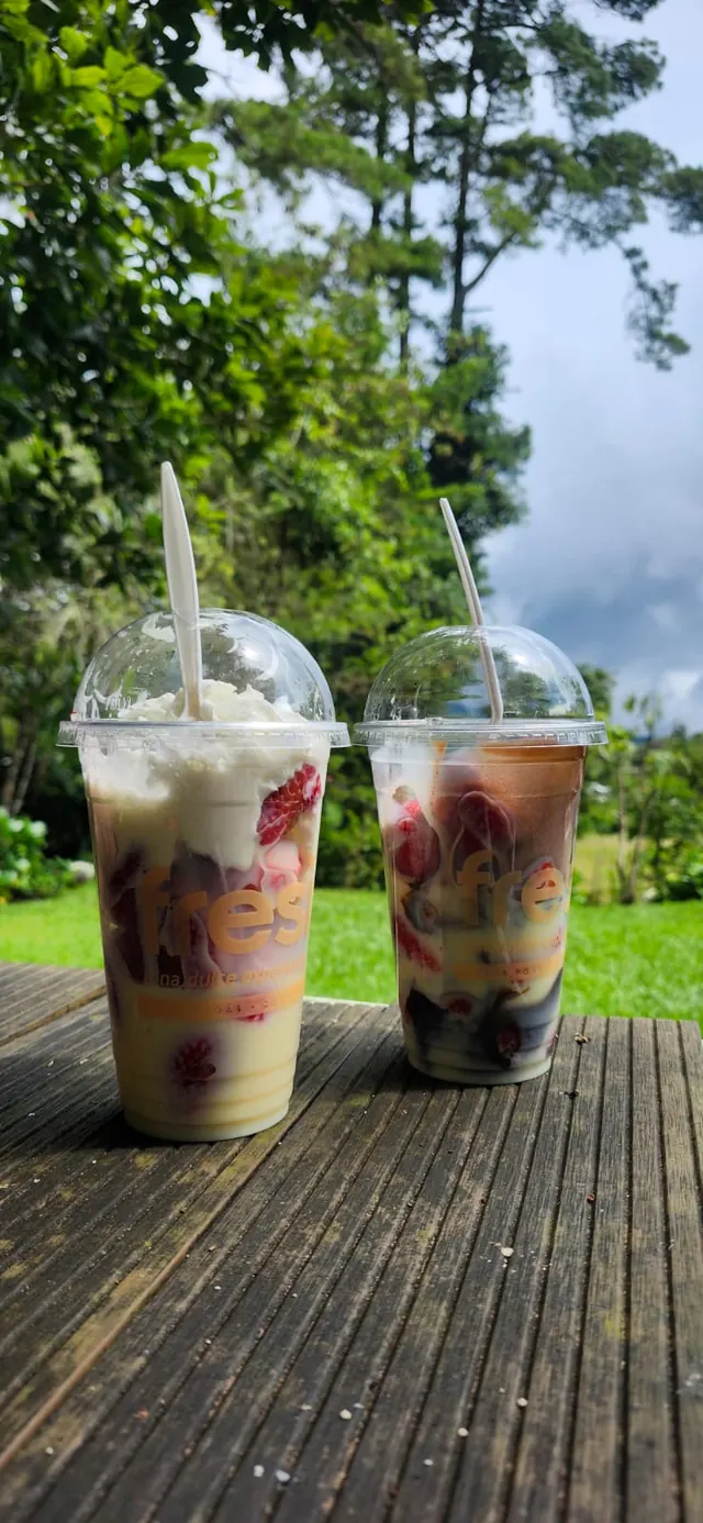 Dos batidos de frutas sobre una mesa de madera al aire libre