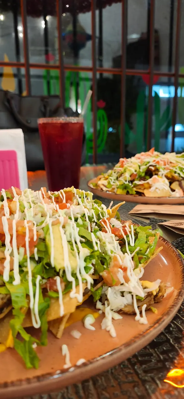 Nachos servidos junto a una bebida roja