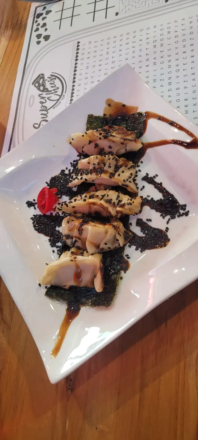 Brochetas de carne sobre salsa oscura en un plato blanco