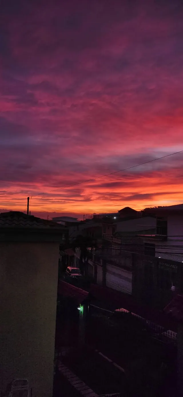 Cielo rojizo al anochecer sobre los techos de la ciudad